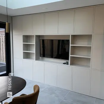 Stylish white built-in TV cabinet with lots of storage space and TV, by Chiel