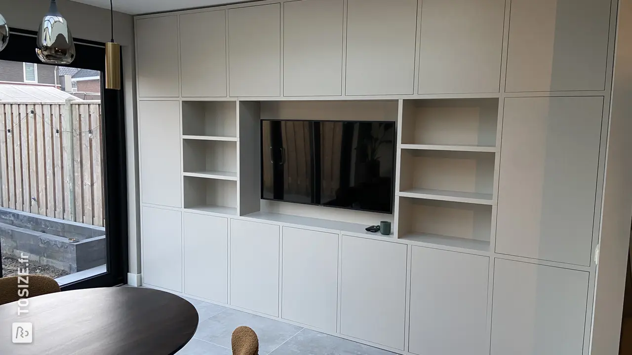 Stylish white built-in TV cabinet with lots of storage space and TV, by Chiel