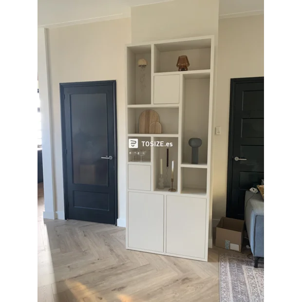 Estantería blanca con compartimentos abiertos y puertas.