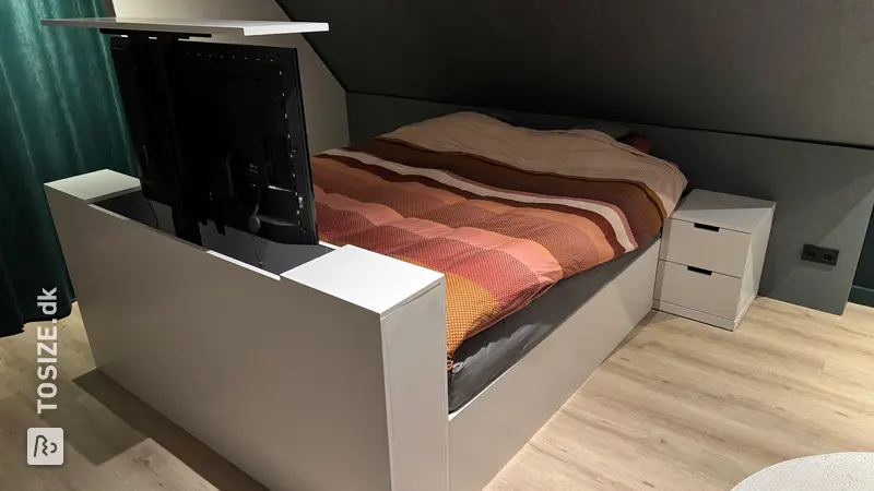 Stylish bed frame with TV lift under sloping roof, by Marc