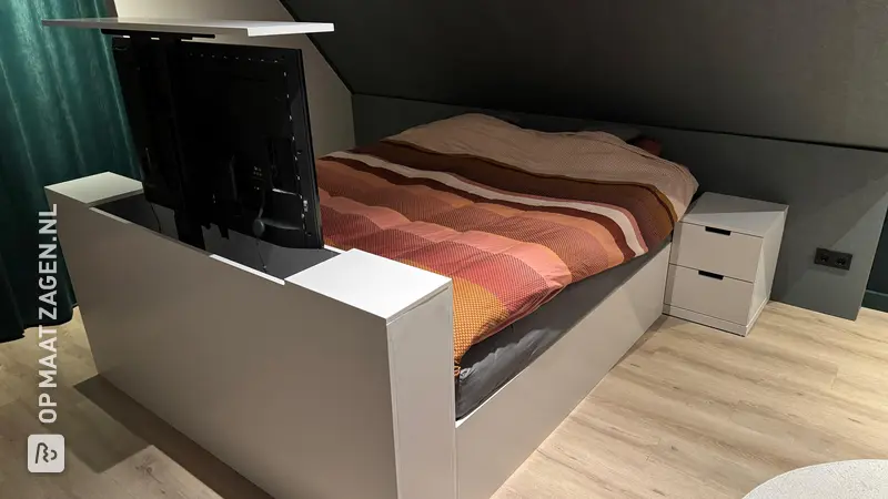 Stylish bed frame with TV lift under sloping roof, by Marc