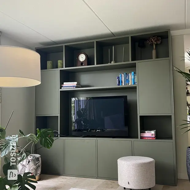 Green cupboard wall with open compartments and doors