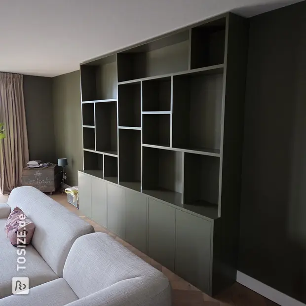 Green cupboard wall with open compartments and doors
