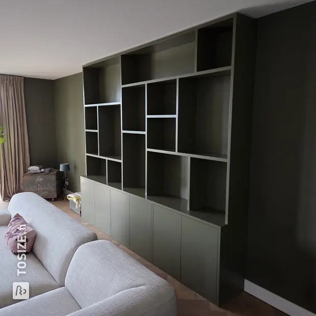 Green cupboard wall with open compartments and doors