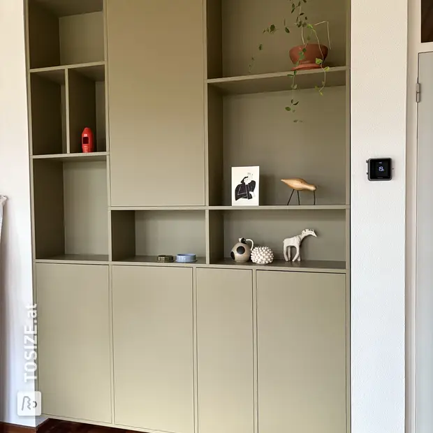 Green cupboard wall with open compartments and doors