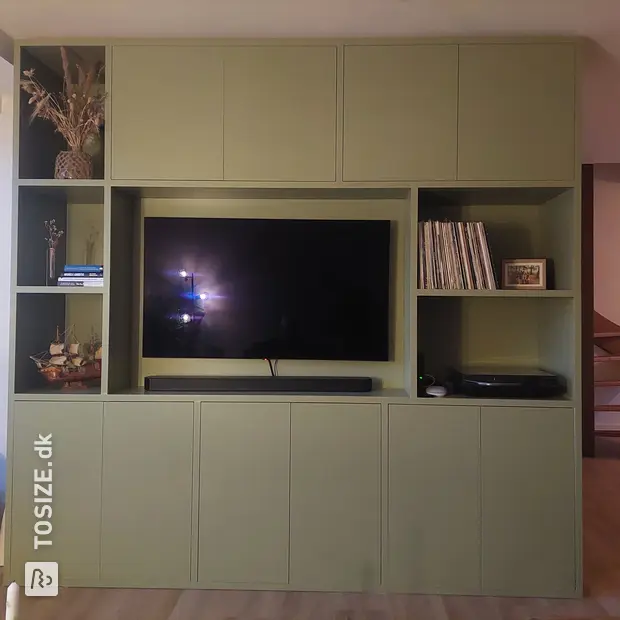 Green cupboard wall with open compartments and doors
