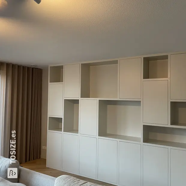Armario de pared blanco con compartimentos y puertas abiertas.