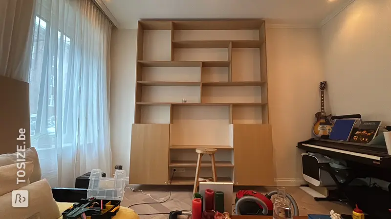 Étagère unique avec placards de cuisine dans le salon, par Jeroen