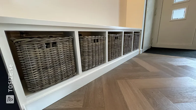 Shelving unit and bench with baskets and a rough wooden back wall, by Remi