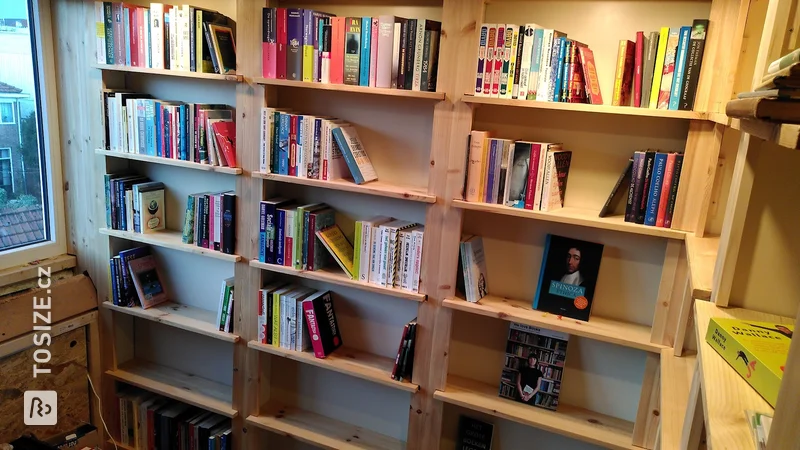 Bookcase wall in the attic made of pine wood, by Daan