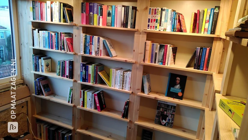 Bookcase wall in the attic made of pine wood, by Daan