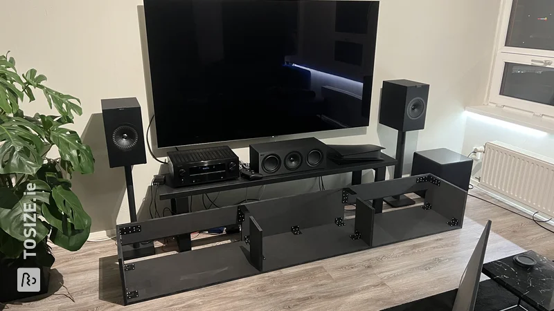 Custom black TV cabinet with space for speaker boxes, by Mert