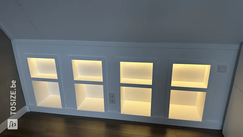 Built-in bookcase in the attic under a sloping roof with LED strips, by Wouter