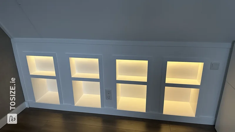 Built-in bookcase in the attic under a sloping roof with LED strips, by Wouter