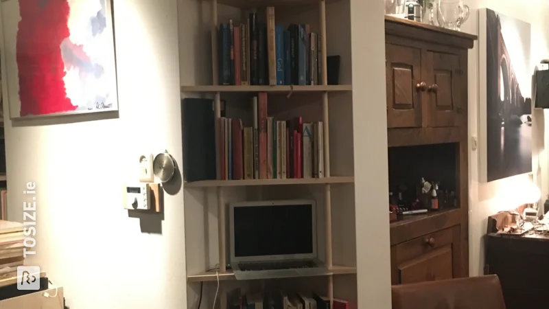 A custom corner cabinet in a niche for books and projector, by John