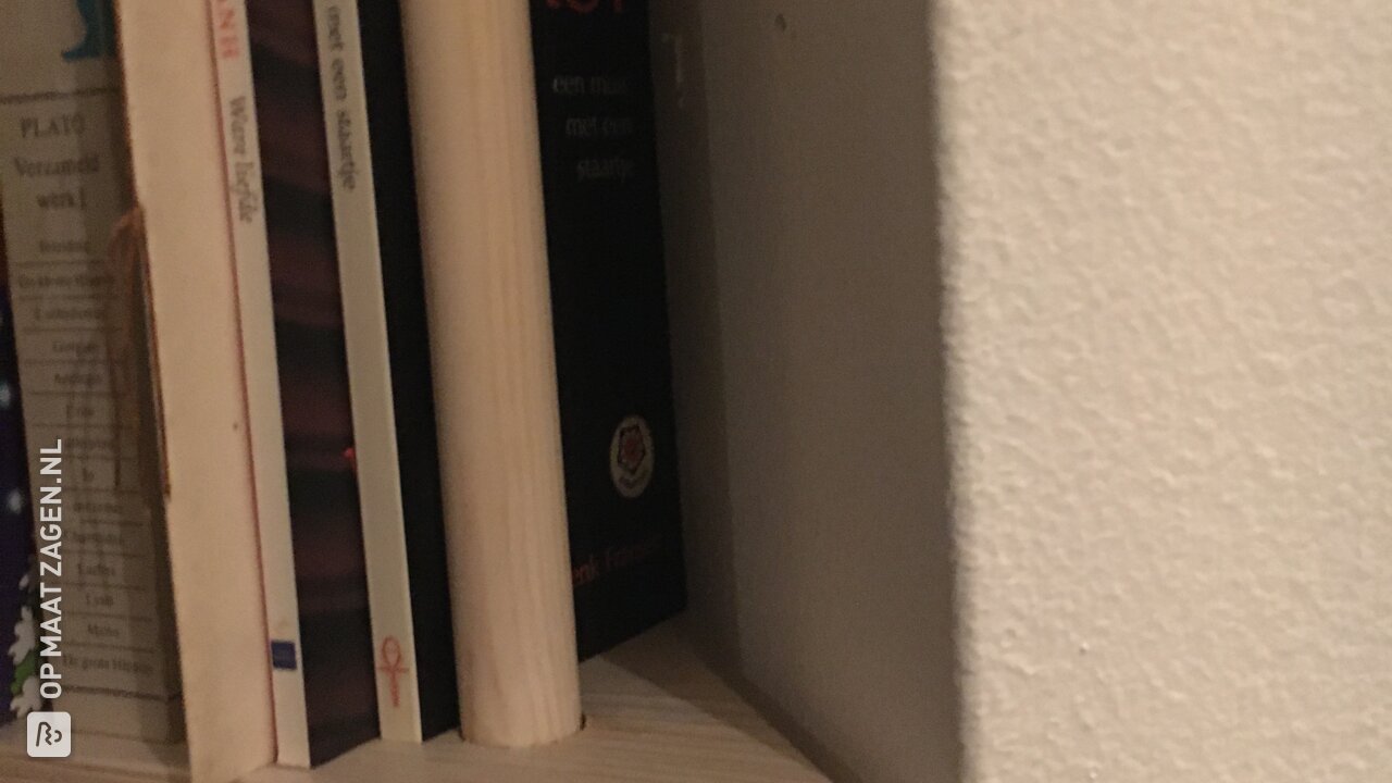 Een hoekkast op maat in een nis voor boeken en beamer, door John