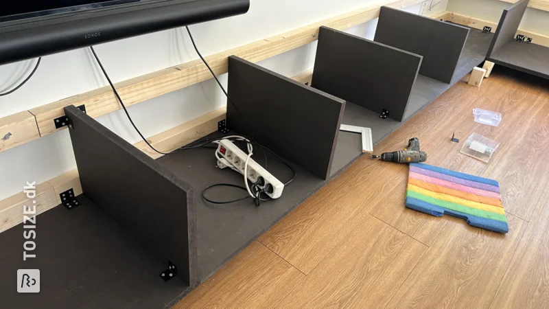 A large homemade floating TV cabinet made of sawn black MDF, by Hans