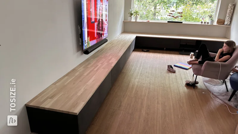A large homemade floating TV cabinet made of sawn black MDF, by Hans