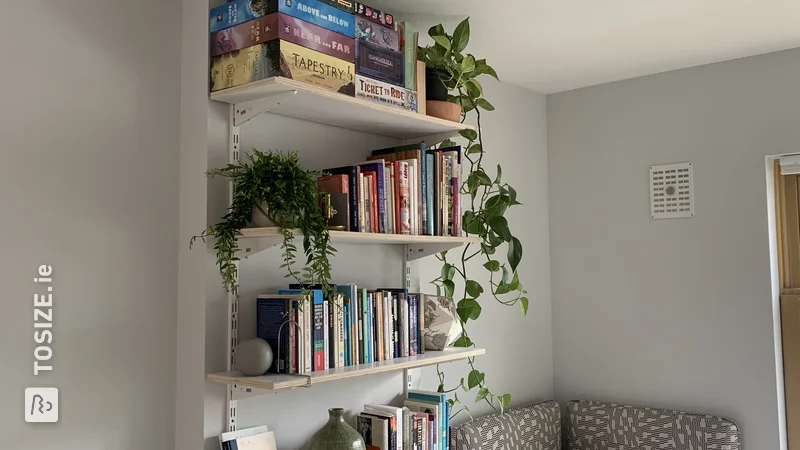 A homemade book wall made of shelves, by Tove