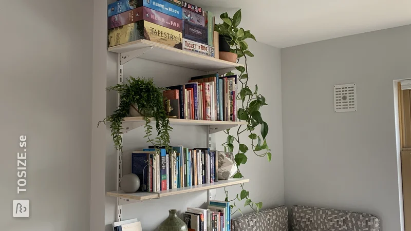 A homemade book wall made of shelves, by Tove