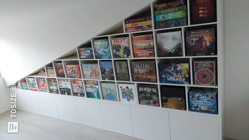 Board game cupboard under sloping roof next to dormer window, by Erik