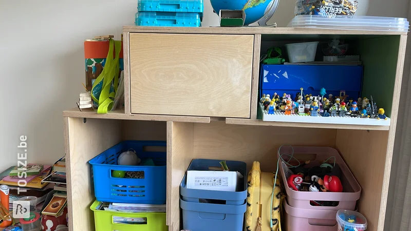 Armoire à jouets unique avec portes et compartiments ouverts en contreplaqué, par Niels