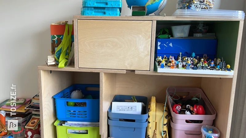 Armoire à jouets unique avec portes et compartiments ouverts en contreplaqué, par Niels