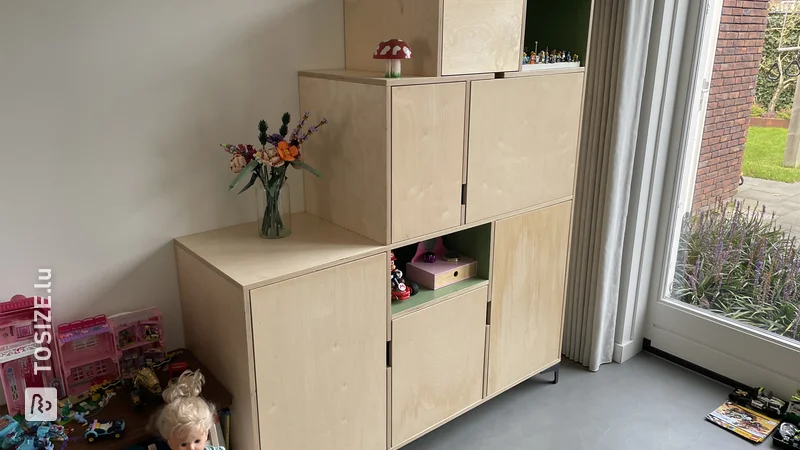 Armoire à jouets unique avec portes et compartiments ouverts en contreplaqué, par Niels